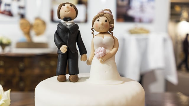 Ein Hochzeitspaar aus Marzipan auf einer Hochzeitstorte.