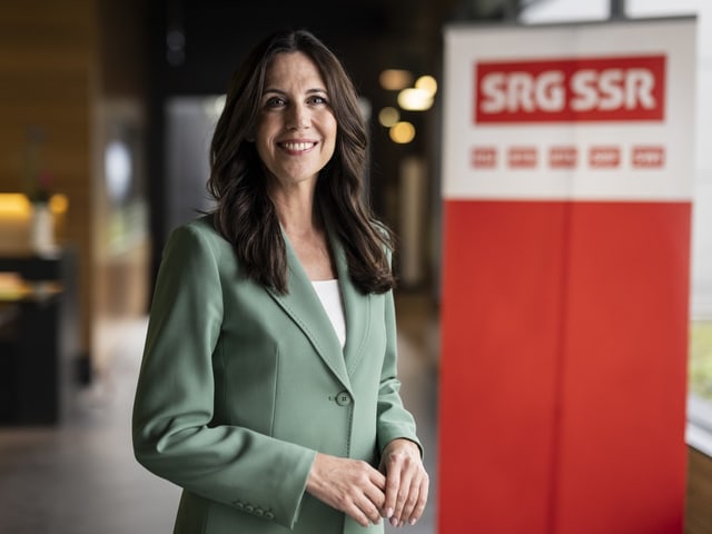 Frau in grünem Blazer vor SRG SSR Schild.