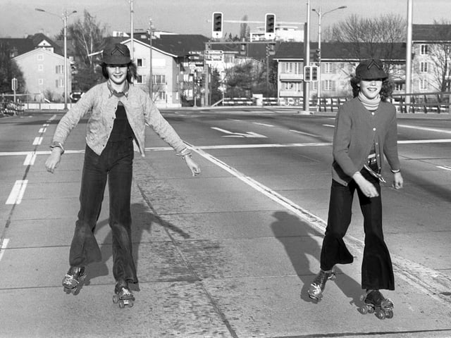 Two girls rollerblading on the streets of Zurich.