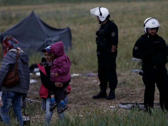 Polizisten vor Flüchtlingen im Lager von Idomeni.