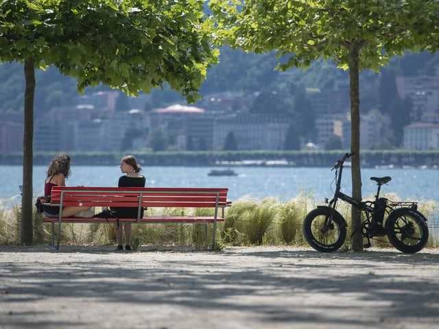 Zwei Personen auf einer Bank am See.