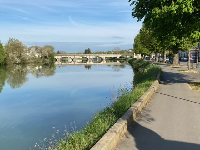 Fluss mit steinerner Brücke und Gehweg.