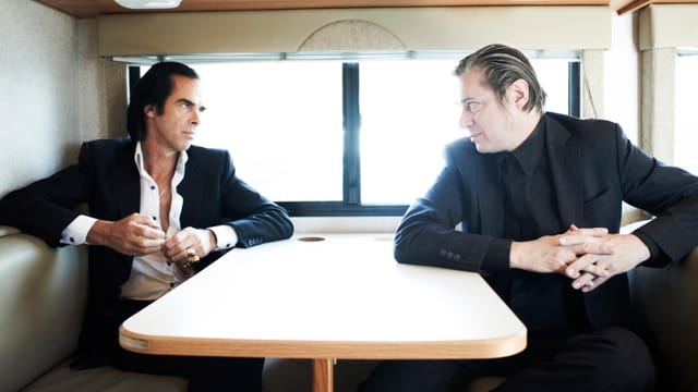 Nick Cave und Blixa Bargeld an einem Tisch