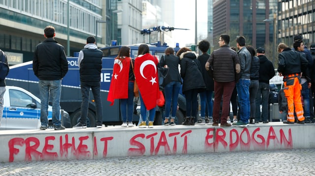 Menschen stehen in einer Strasse, auf einer Mauer steht "Freiheit statt Erdogan".