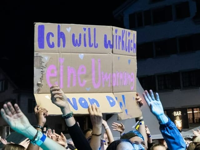 Ein Schild im Publikum mit der Aufschrift «Ich will wirklich eine Umarmung von dir!»