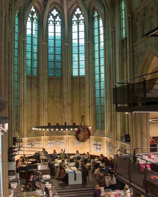 Moderne Bibliothek in einer Kirche mit hohen Fenstern und Besuchern.