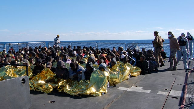 Bootsflüchtlinge auf Schiffsdeck sitzend