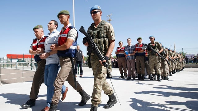 Türkische Soldaten führen die Angeklagten in Reih und Glied zum Gericht. 