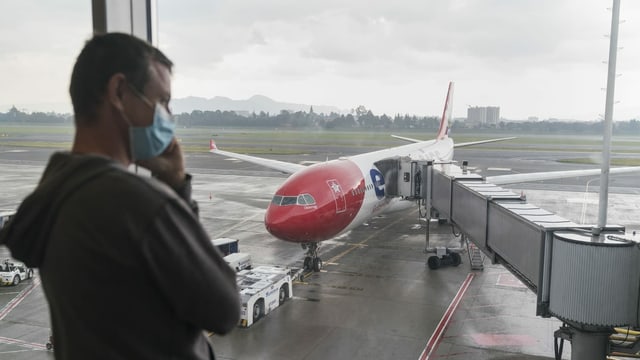 Mann mit Maske vor Flugzeug