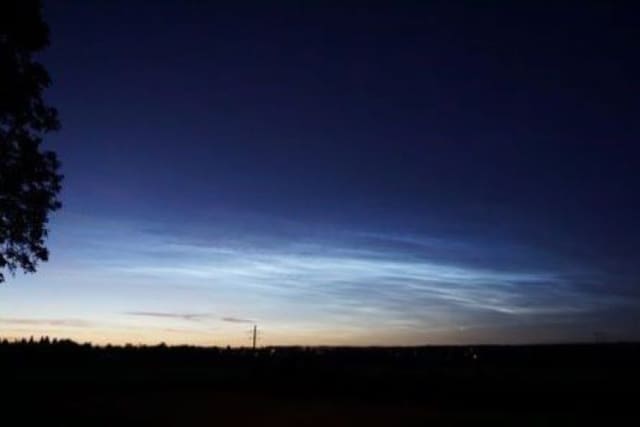 Silbern leuchtende Nachtwolken am dunklen Himmel.