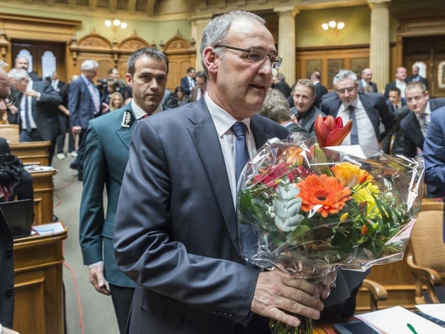 Guy Parmelin in the House of the National Council with a bouquet of flowers.