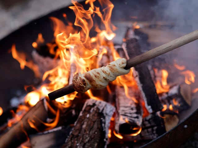 Stockbrot über einem offenen Feuer.