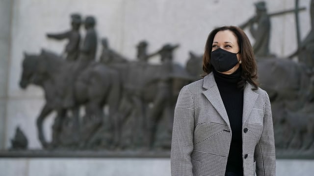 Harris in a mask in front of a monument.