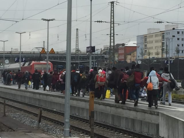 Dutzende Menschen auf einem Bahnhof-Perron.