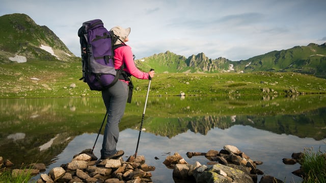 Wanderin mit Rucksack vor einem Bergpanorama.