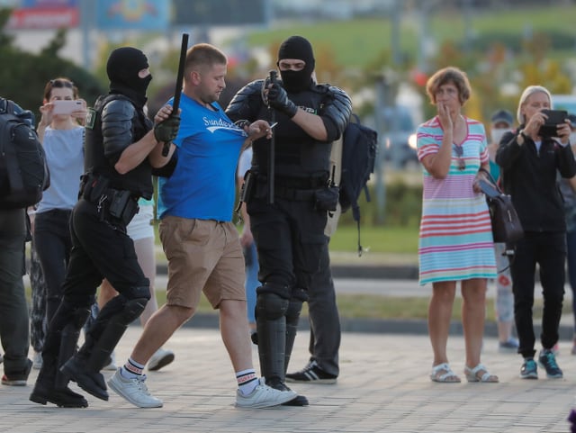 Ein Mann wird von zwei uniformierten Polizisten abgeführt.