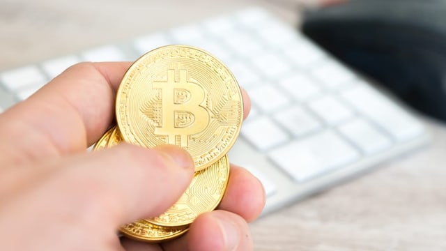 Hand, die physische Bitcoin-Münzen hält