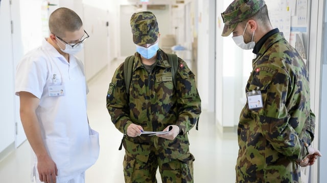 Two soldiers and a doctor in conversation.