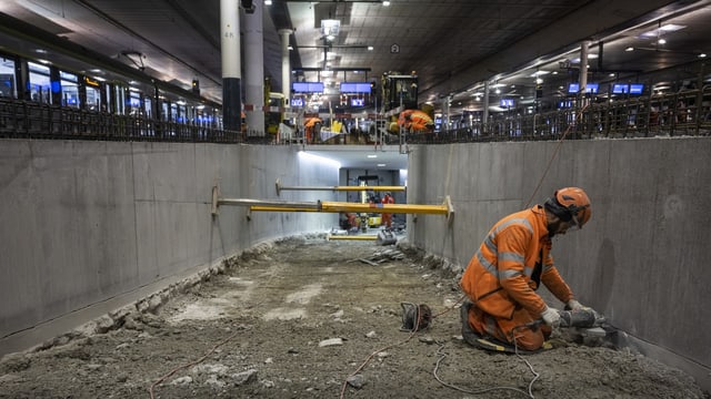 Ein Bauarbeiter schleift an der Passarellenwand am Bahnhof Bern. 