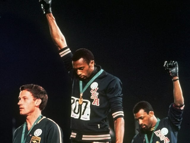 Tommie Smith und John Carlos strecken ihre Hände zum Himmel, um gegen die Rassentrennung in den USA zu protestieren.