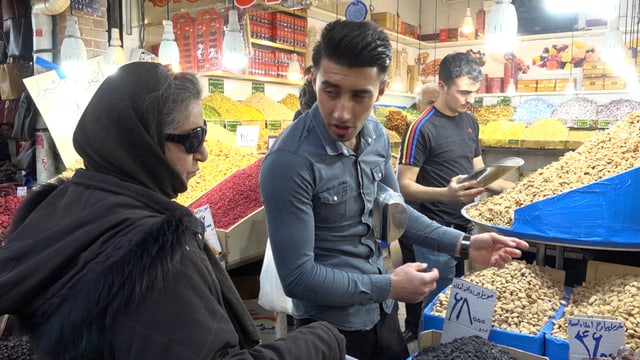 Eine Frau handelt auf dem Gemüsemarkt.