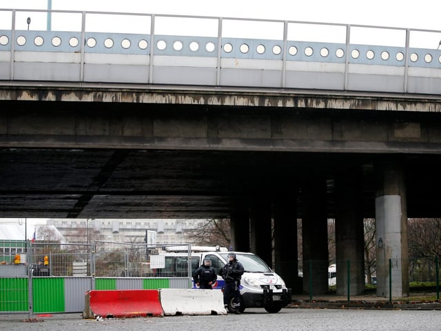 Bewaffnete Polizisten stehen unter einer Brücke.