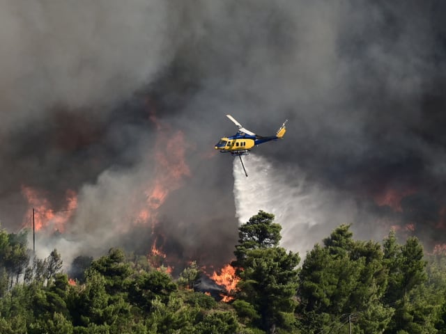 Ein Hubschrauber löscht einen Waldbrand aus der Luft.