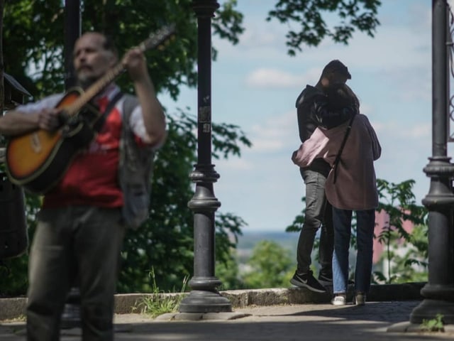 Pärchen, davor spielt ein Musiker