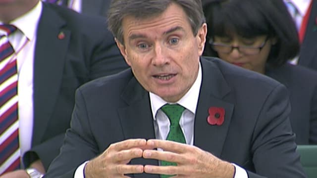 Sir John Sawers an einem Sitzungstisch.