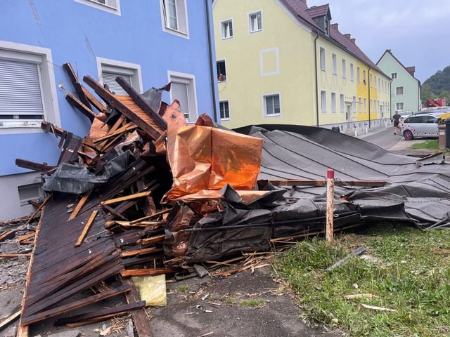 Neben einem Haus liegen zertrümmerte Dachteile.