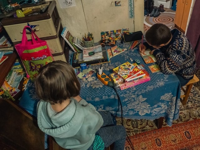 Die zwei Kinder sitzen am Tisch mit Schulheften