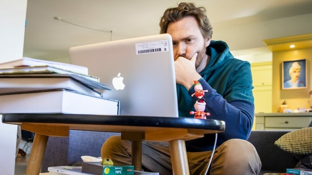 A man works on his sofa at the computer