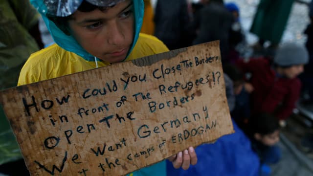 Flüchtlingsjunge hält Schild hoch