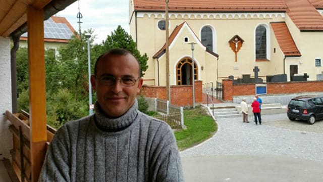 Hassan Hammed lächelnd vor einer Kirche. 