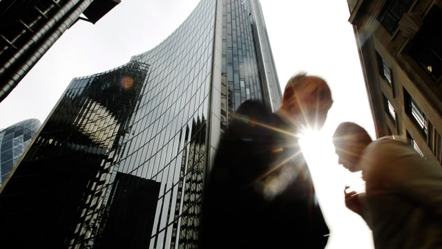 Symbolbild: Zwischen den Hochhaustürmen der Canary Wharf in London gehen Menschen vorbei.