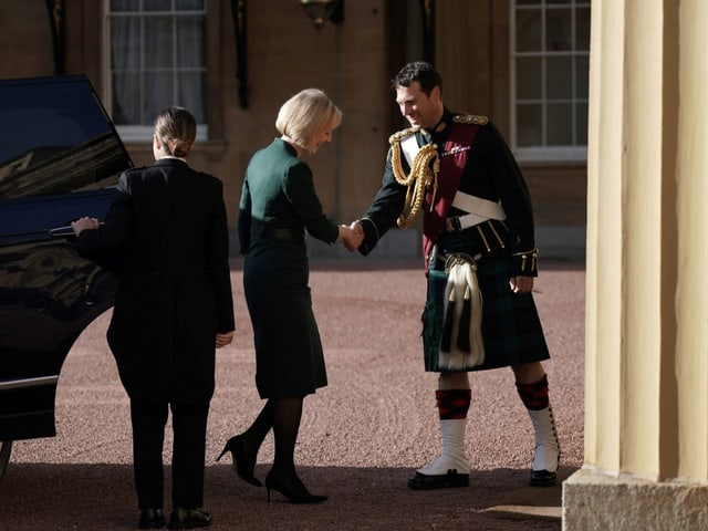 Liz Truss schüttelt einem Mann in Tracht die Hand vor dem Buckingham-Palast.