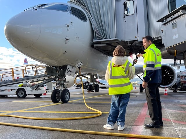 Zwei Menschen mit gelben Leuchtwesten stehen vor einem Flugzeug. 