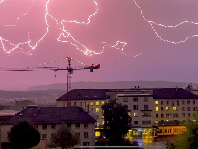 Mehrere Blitze an rot gefärbtem Himmel über Gebäude