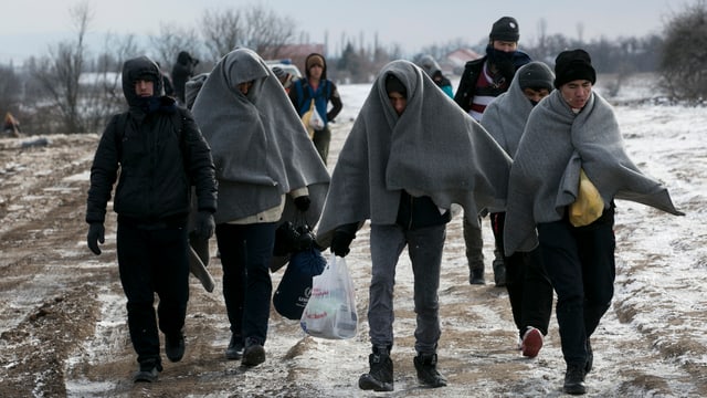 Flüchtlinge mit Wolldecken um den Kopf