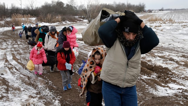 Eine Gruppe von Flüchtlingen geht über ein gefrohrenes Feld.