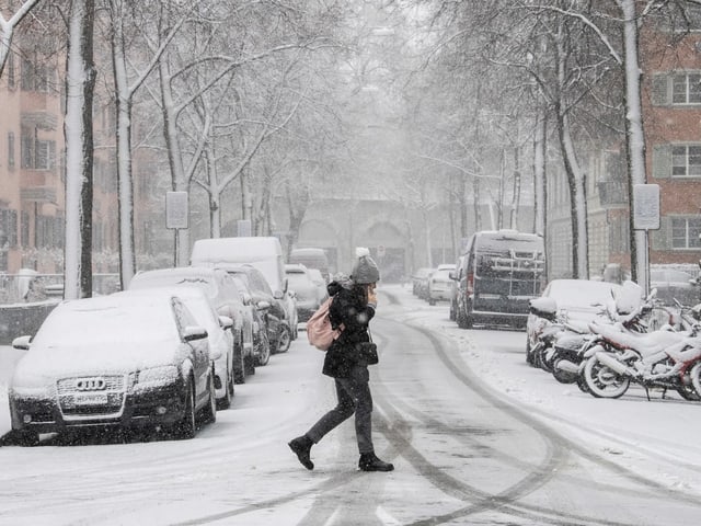 Woman crosses a snowy street in Zurich.