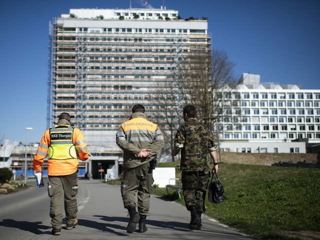 Ein Zivilschützer und ein Angehöriger des Militärs gehen Richtung Spital.