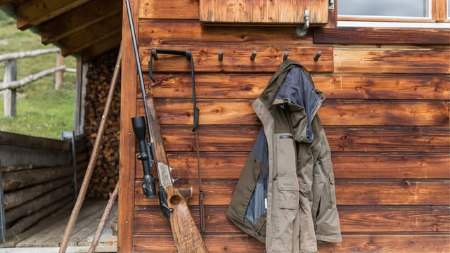 Waffe und Jacke, aufgehängt vor Hütte