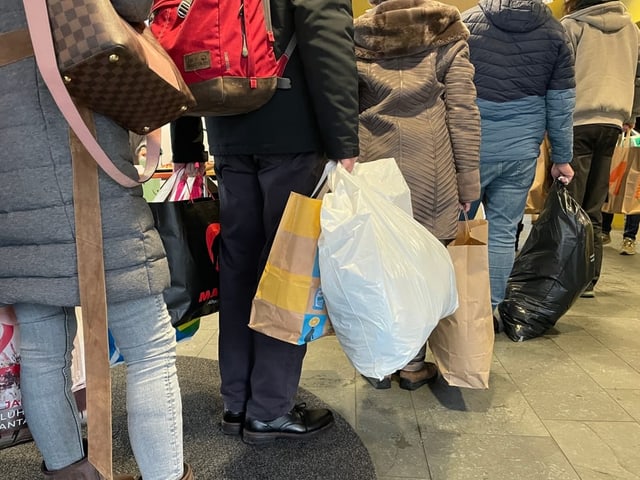 Menschen mit Taschen stehen Schlange