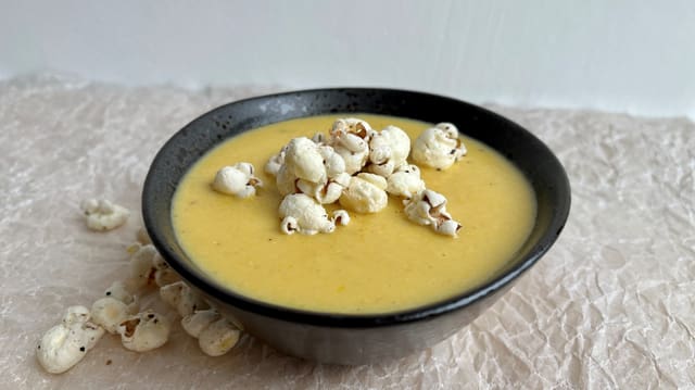 Schwarze Schale mit Suppe aus Büchsenmais und Butterpopcorn aös Topping.