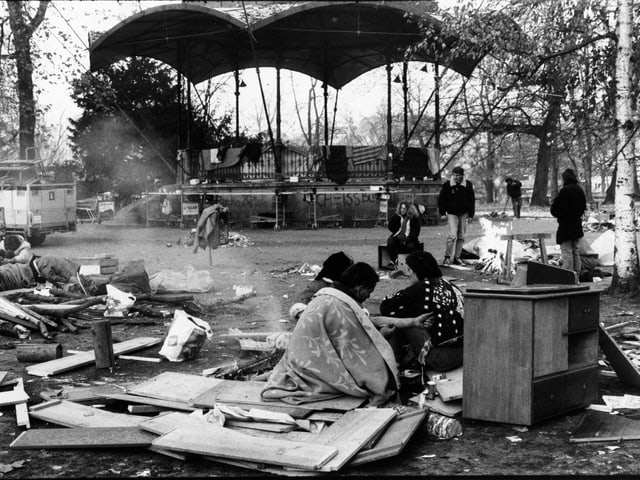 Schwarzweiss Fotografie, Drogensüchtige am Boden und auf Kartonschachteln im Park.