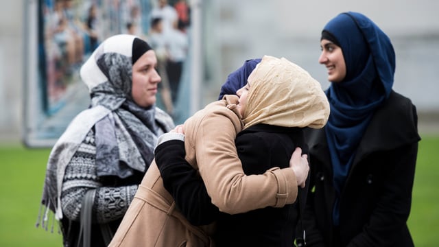 Frauen mit Kopftuch umarmen sich