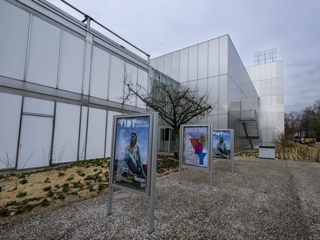 Modernes Gebäude mit Werbeplakaten im Vordergrund.