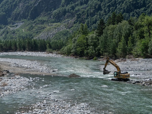 Bagger arbeitet in einem Flussbett.