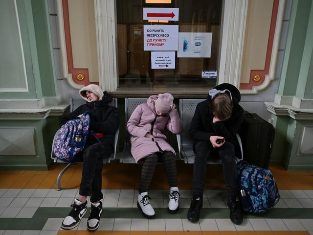 Drei junge Menschen schlafend auf einer Parkbank.